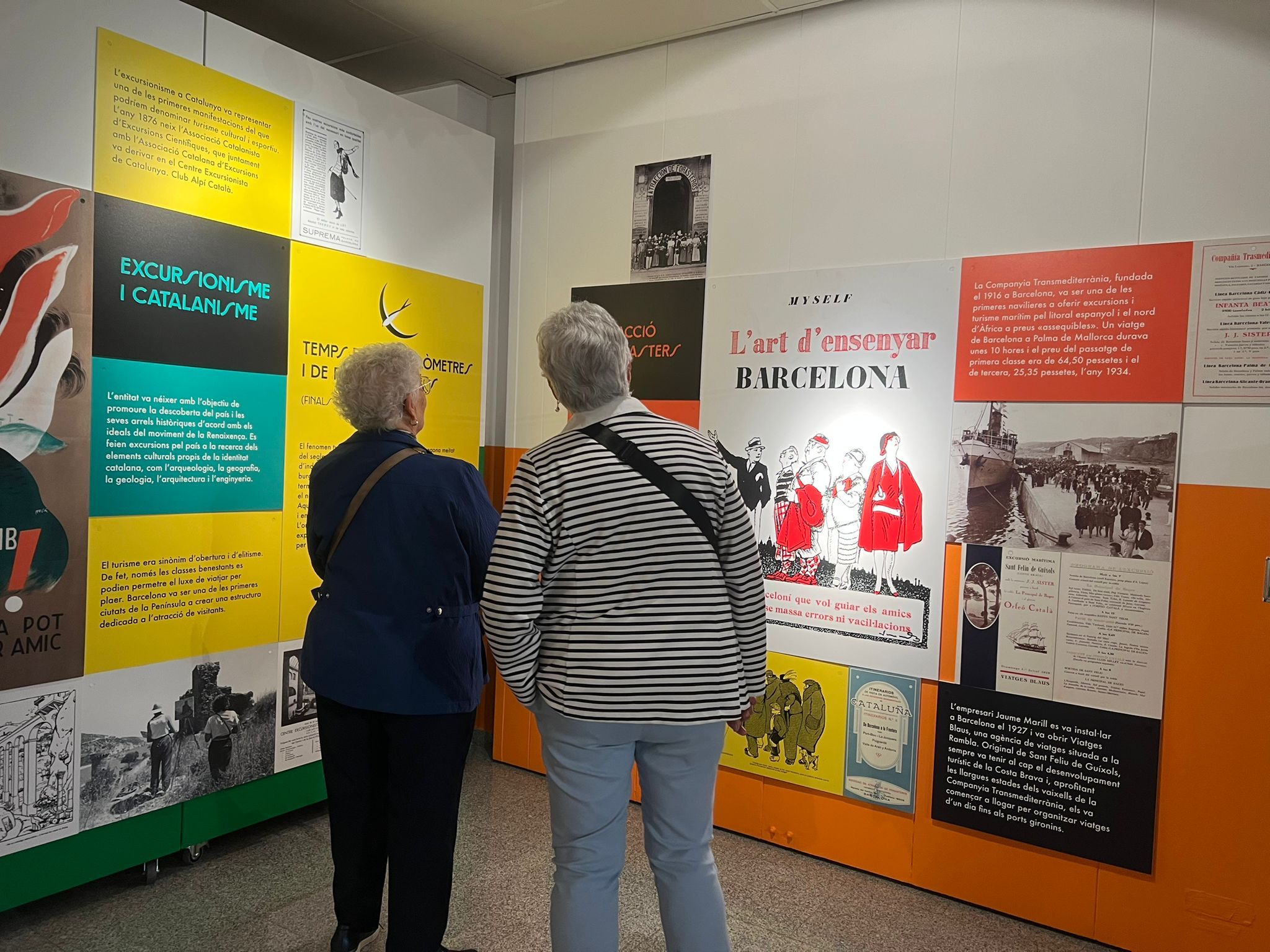 Dues persones es miren l'exposició 'Obert per vacances'. Foto: Laia Jubany