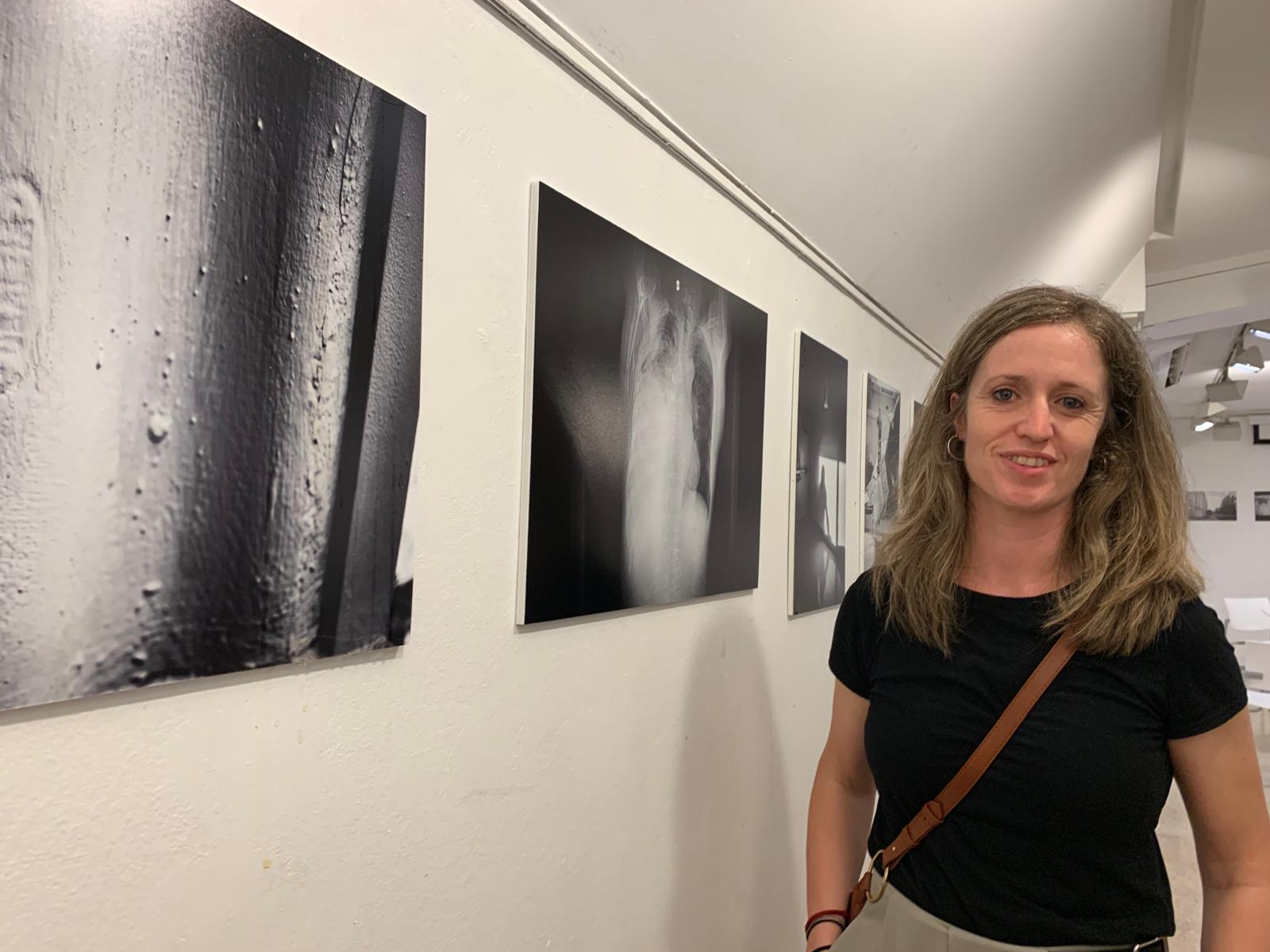 Sílvia Isach, al costat de la fotografia d’una coberta d’uralita amb capes de pintura i les gotes d’aigua que s’hi van filtrar durant la tempesta. FOTO: Judit Josa